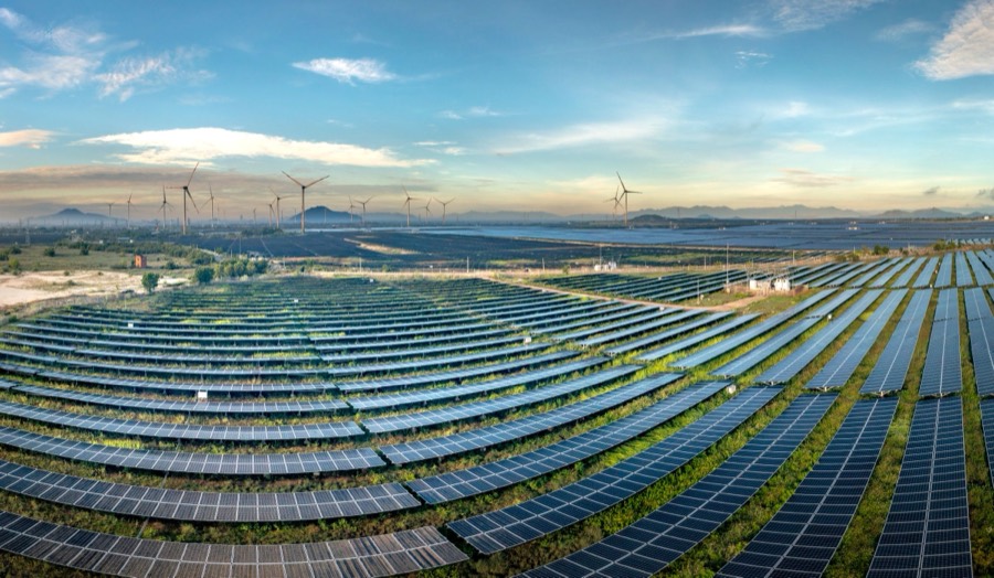 Photovoltaic solar plant with wind turbines at sunrise